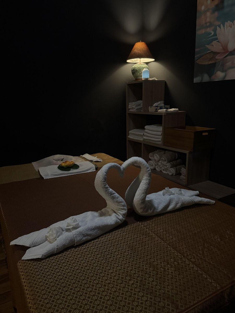 Zu einem Herz gefaltete Schwan-Handtücher auf der Massageliege