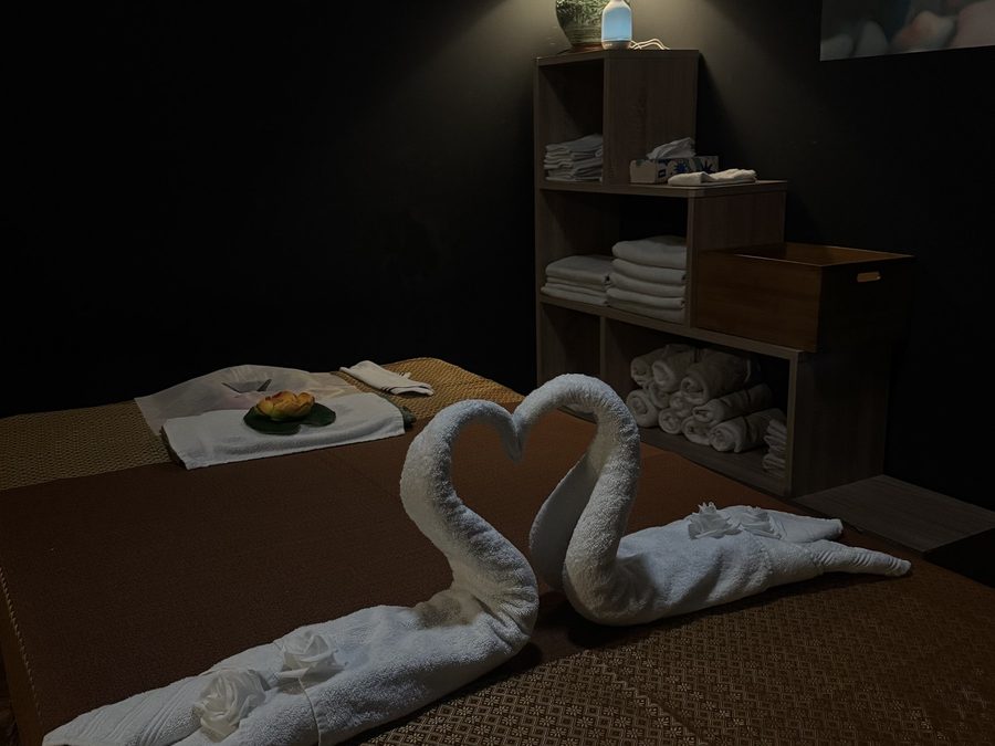 Behandlungsraum mit Massageliege und zu Schwänen gefalteten Handtüchern