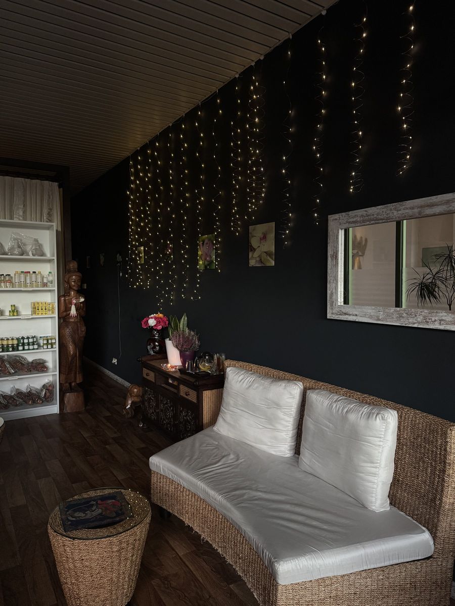 Gemütlicher Wartebereich mit Lichtervorhang, Rattan-Sofa und Regal mit Pflegeprodukten